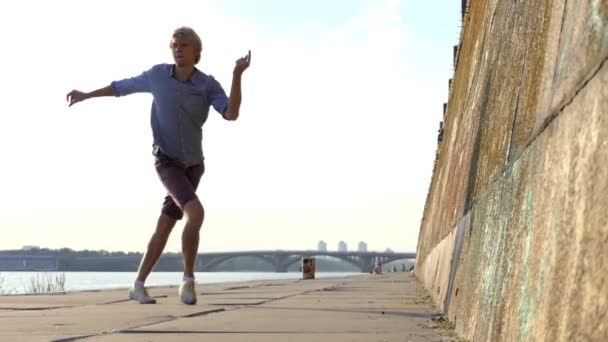 Energetic Man Dances Disco sur une rive avec un haut mur de pierre à Slo-Mo — Video