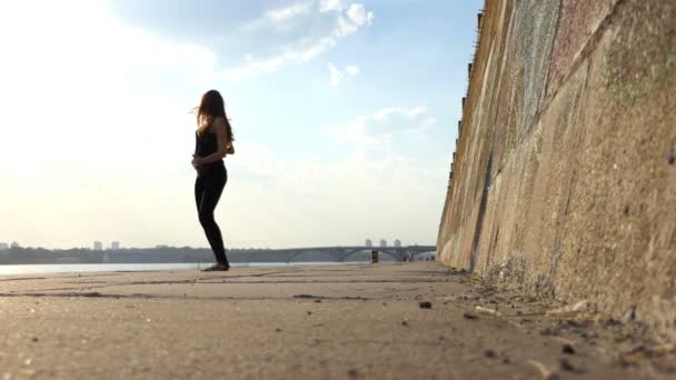 Fin gravid kvinna i svart kostym danser på Riverbank en solig dag i Slo-Mo — Stockvideo