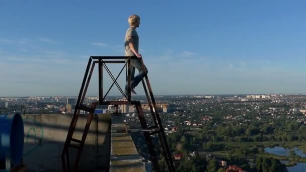 Jonge man maakt een longe op een trap aan een hoog gebouw — Stockvideo