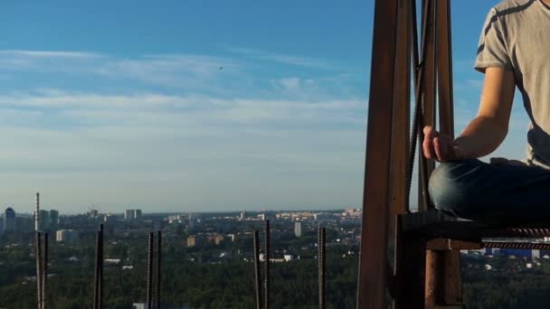 Young man sits in lotus asana on a metalic staircase of a building — Stock Video