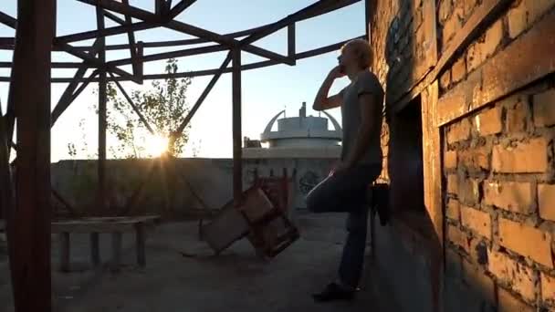 Ung man står på en byggarbetsplats och samtal — Stockvideo