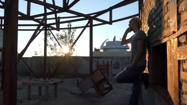 Joven habla por su teléfono inteligente en un sitio de construcción en slo-mo — Vídeos de Stock