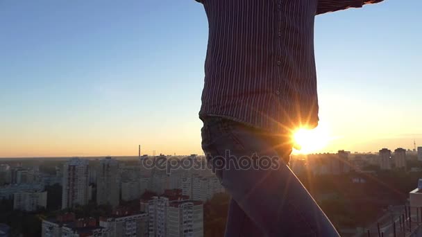 Ризикований хлопець стоїть на високому бетонному краю на заході сонця влітку . — стокове відео