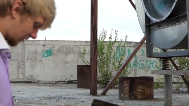 Blond man sits on a construction place and works at his laptop — Stock Video