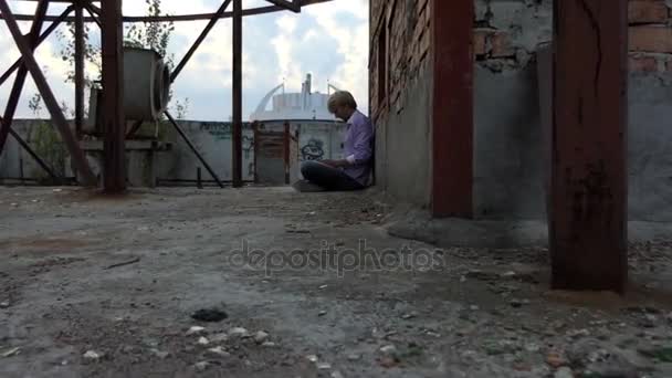 Een creatieve man wordt afgedrukt op zijn laptop op een dak-o een gebouw in slo-mo — Stockvideo