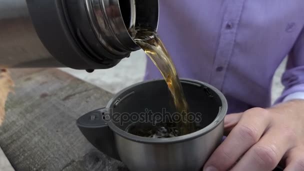 Young man pours green tea from a flask in his cup in slo-mo — Stock Video