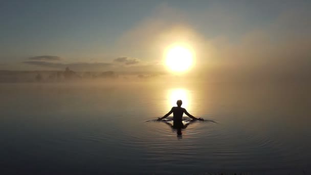 Jeune homme fait des vagues dans un lac au coucher du soleil à Xo@-@ mo — Video