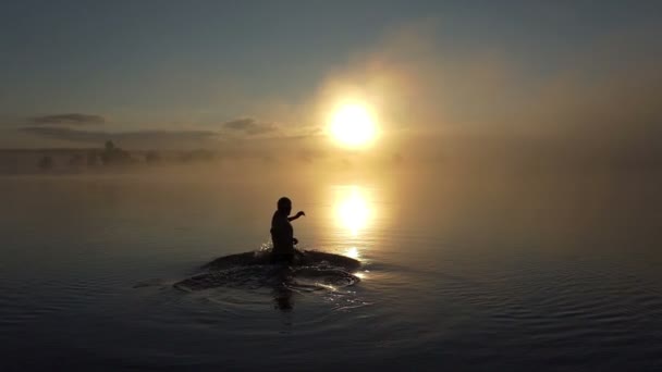 Jovem corre em um lago e olha para o pôr do sol em slo-mo — Vídeo de Stock