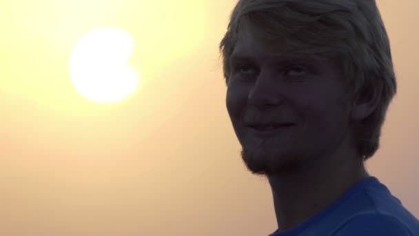 Joven sonríe al aire libre en una espléndida puesta de sol en slo-mo — Vídeo de stock