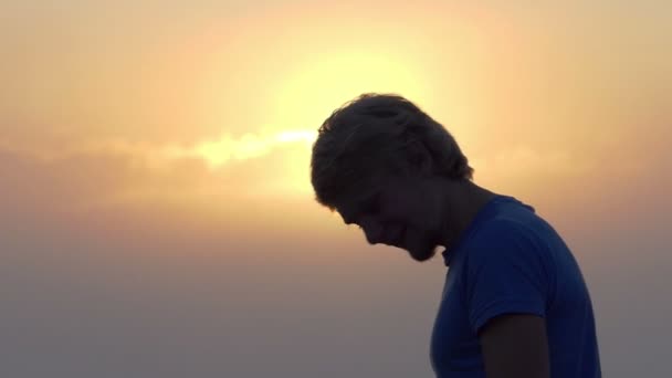 Ung man underhåller och skakar på huvudet vid solnedgången i slo-mo — Stockvideo