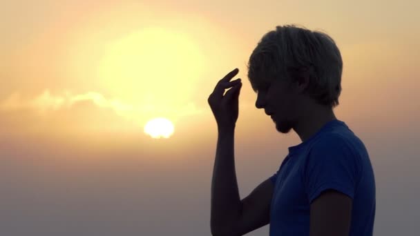 若い男はスローモーションで素晴らしい夕日を彼自身を交差させる — ストック動画