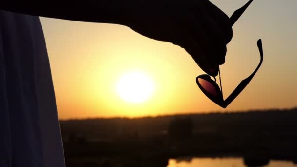 Joven morena se pone sus gafas de sol en una puesta de sol romántica en Slo-Mo — Vídeos de Stock