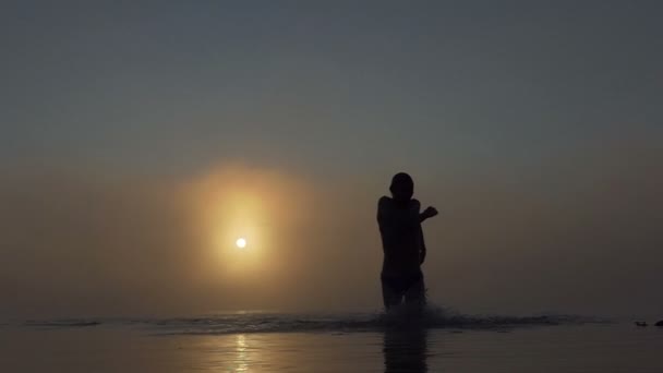 Mladý muž vede od zamlžené jezero při západu slunce v slo-mo