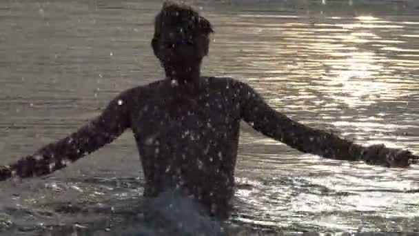 Blond homme joue t dans un lac au coucher du soleil en été à Xo@-@ mo — Video