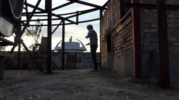 Giovane uomo lancia un cellulare su un muro di mattoni al tramonto in slo-mo — Video Stock