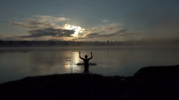 Hombre rubio juega con las aguas del lago cubiertas de neblina en slo-mo — Vídeo de stock