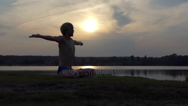 Yogi ember ül a Lotus, és emeli a kezét, napnyugtakor a slo-mo — Stock videók