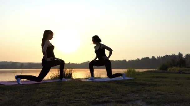Fitness at sunset near lake - two young and slender girls. — Stock Video