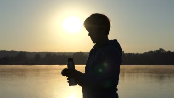 Жінка ковтає колбу з кавою на заході сонця в 4k — стокове відео