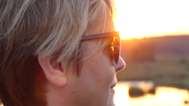 Frau mittleren Alters nimmt Sonnenbrille bei Sonnenuntergang in Zeitlupe ab. — Stockvideo