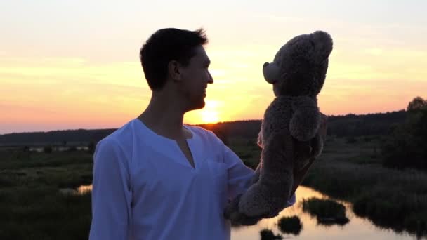 Man with big bear plays near forest lake. — Stock Video