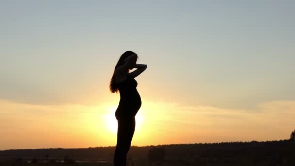 Jong zwanger meisje schud haar haren in slow motion bij zonsondergang. — Stockvideo