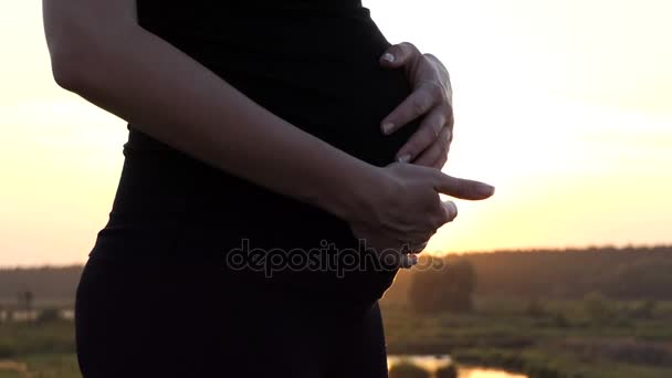 Händerna på gravid kvinna stokes hennes mage. — Stockvideo