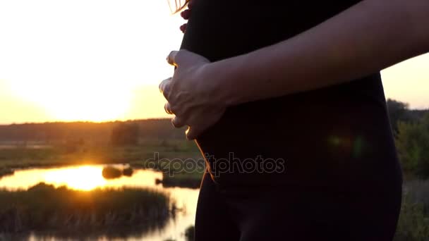 Chica embarazada bailando y tocándose el estómago en cámara lenta al atardecer . — Vídeos de Stock