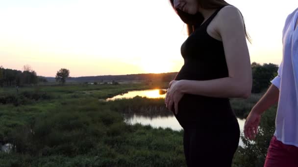 Atardecer increíble - hombre abrazo mujer embarazada en cámara lenta . — Vídeo de stock