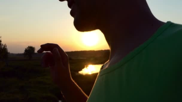 Fiatal férfi ruhák napszemüveg, napnyugtakor a lassú mozgás. — Stock videók