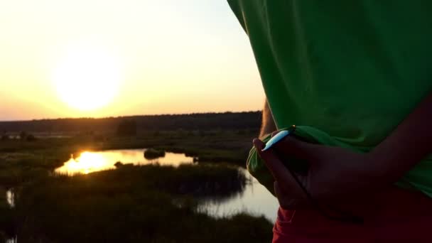 Man in groene t-shirt schone zonnebril bij zonsondergang in real-time. — Stockvideo