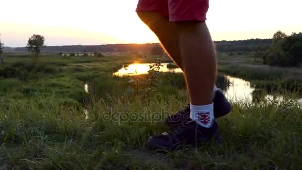 Adam yavaş gün batımında yürüyüş bacaklar. — Stok video