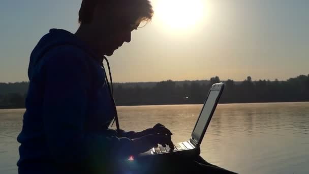 Eine Frau mittleren Alters tippt bei Sonnenuntergang auf einem Laptop — Stockvideo