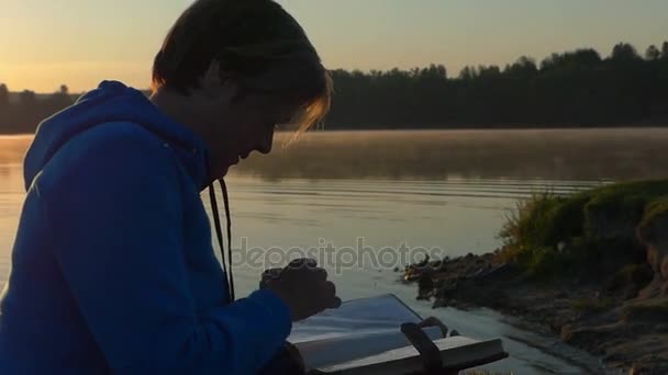 Frau mittleren Alters blickt bei Sonnenuntergang auf ihr Fotoalbum — Stockvideo
