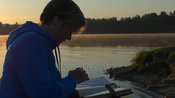 Женщина средних лет смотрит на свой фотоальбом на закате — стоковое видео