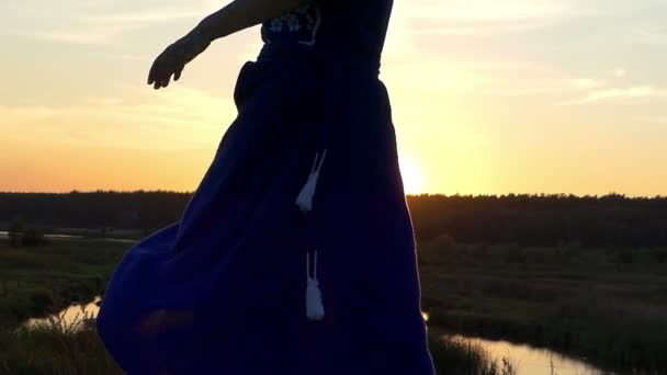 Hermosa mujer ondea el dobladillo de su vestido al atardecer — Vídeos de Stock