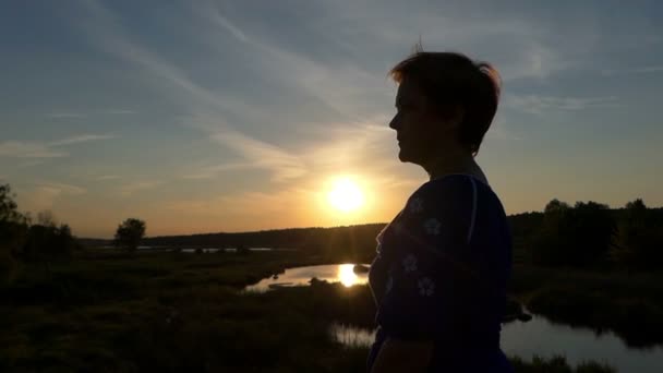 Aantrekkelijke vrouw zet op zonnebril bij een prachtige zonsondergang in slo-mo — Stockvideo