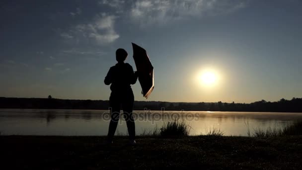 Femme divertissante tourne son parapluie brun au coucher du soleil à the... — Video