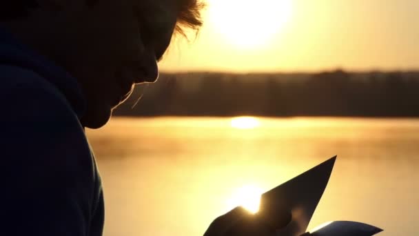 Leende kvinna tittar på foton på en sjö vid solnedgången — Stockvideo