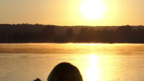 Zamlžené jezero a ženy při pohledu na foto album při západu slunce v slo-mo — Stock video