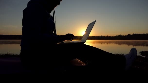 Középkorú író típusok egy mese, a számítógépen a naplemente — Stock videók