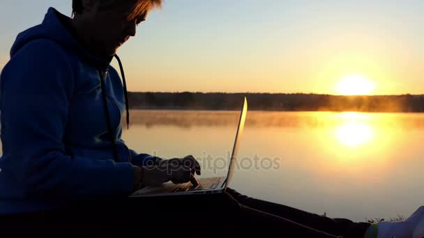 Mujer de ensueño imprime una historia corta en una orilla del lago — Vídeo de stock