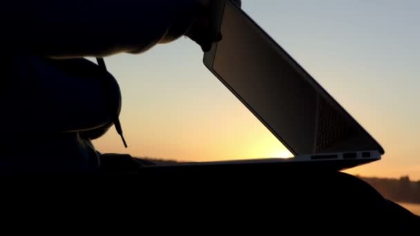 Female hands open a laptopn on a lake bank at sunset — Stock Video