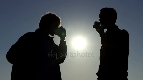 Twee jonge mannen drinken hete thee bij een schilderachtige zonsondergang in 4k — Stockvideo