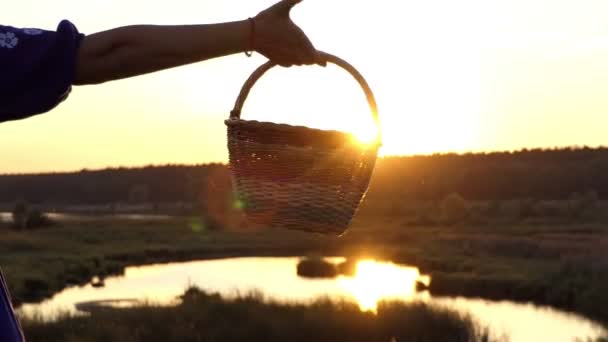 Weibliche Hand schwingt einen Folk-Korb bei Sonnenuntergang in slo-mo — Stockvideo