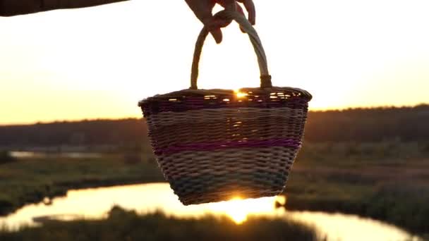 Kvinnlig hand roterar en folklig korg på sjön bank vid solnedgången i slo-mo — Stockvideo