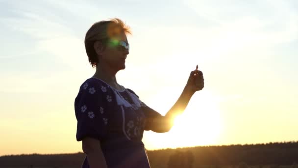 Güneş gözlüklü kadın bir spinner günbatımında çekimde rulo — Stok video
