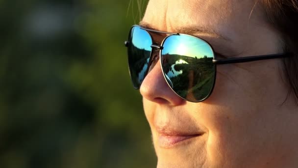 Belle femme en lunettes de soleil sourit à l'extérieur au coucher du soleil — Video