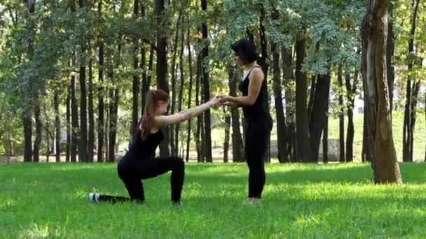 Dos jóvenes entrenan en trajes negros en un parque — Vídeos de Stock