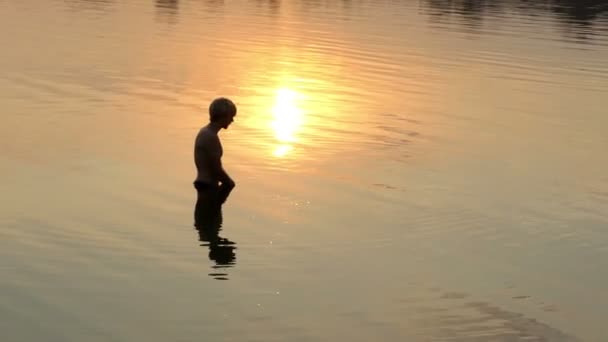 Блондин делает брызги в озере на закате в сло-мо — стоковое видео